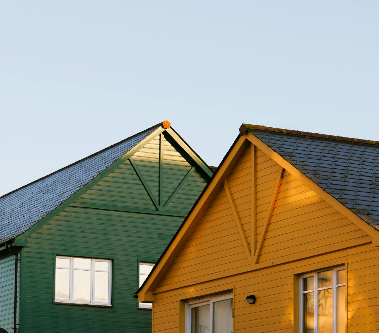 Green and yellow wooden house roofs under clear sky at sunset.